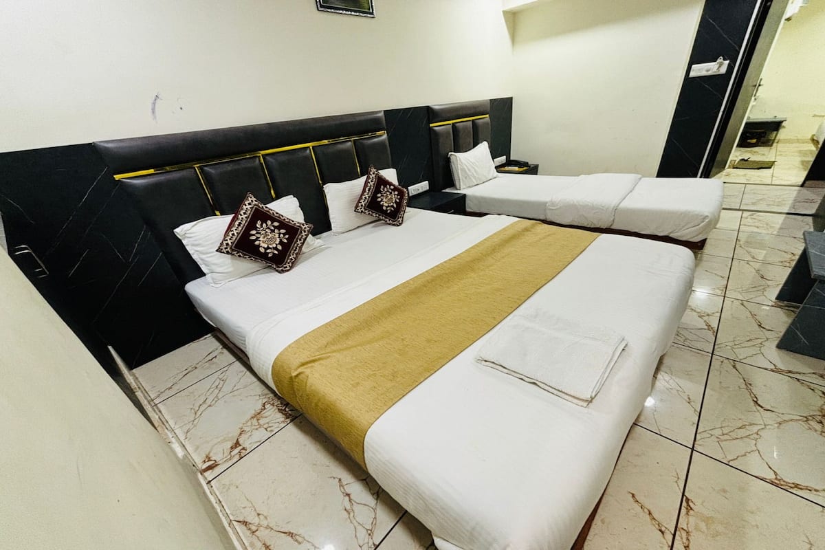 Habitación de hotel con dos camas, piso de baldosas de mármol y cabecero negro con detalles dorados.