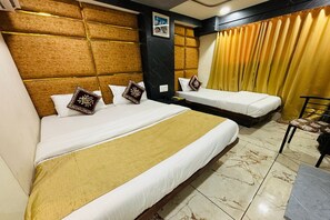 Een hotelkamer met twee bedden, een slaapbank, een stoel en een kleine tafel.
