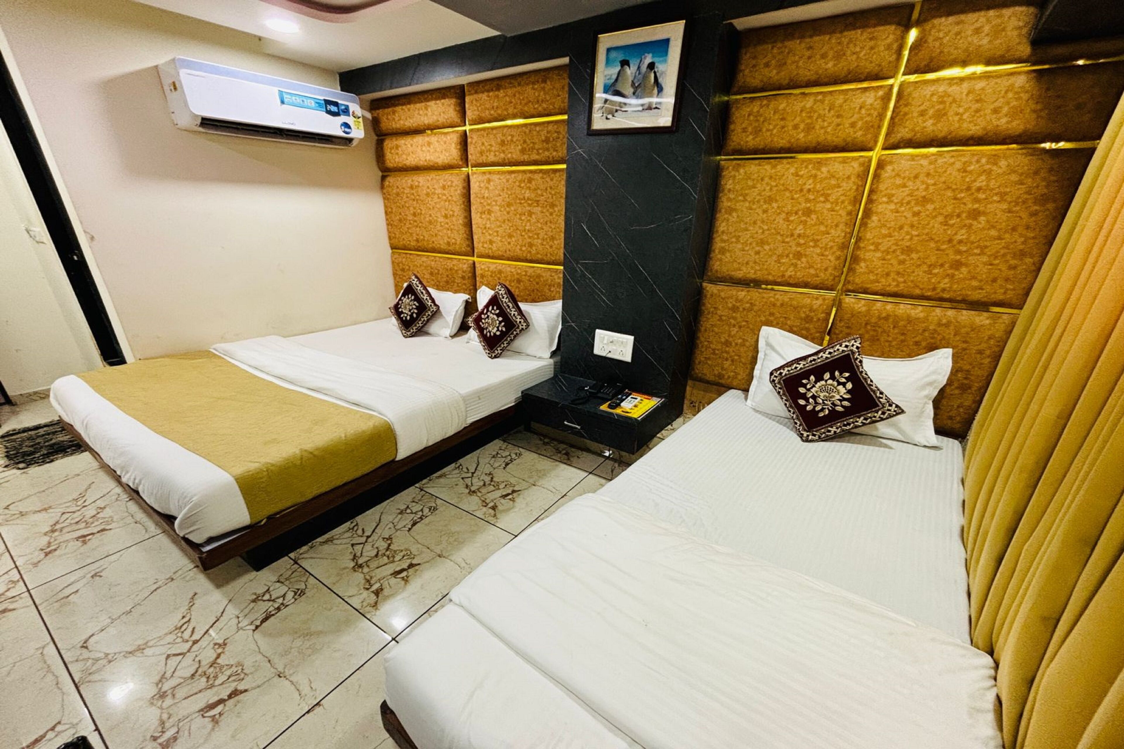 A hotel room with two single beds, a marble-tiled floor, a wall-mounted air conditioner, and a framed picture above the headboard.