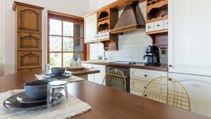 Una cocina con armarios de madera, una cafetera y una mesa de comedor con platos y un tazón.