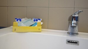 A yellow waste basket with some items and a modern faucet on a white sink. - Housestation S (Palermo)