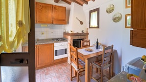 A rustic kitchen with wooden cabinets, a gas stove, and a dining table with chairs.