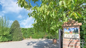 A gravel driveway leading to a brick entrance with a signboard.
