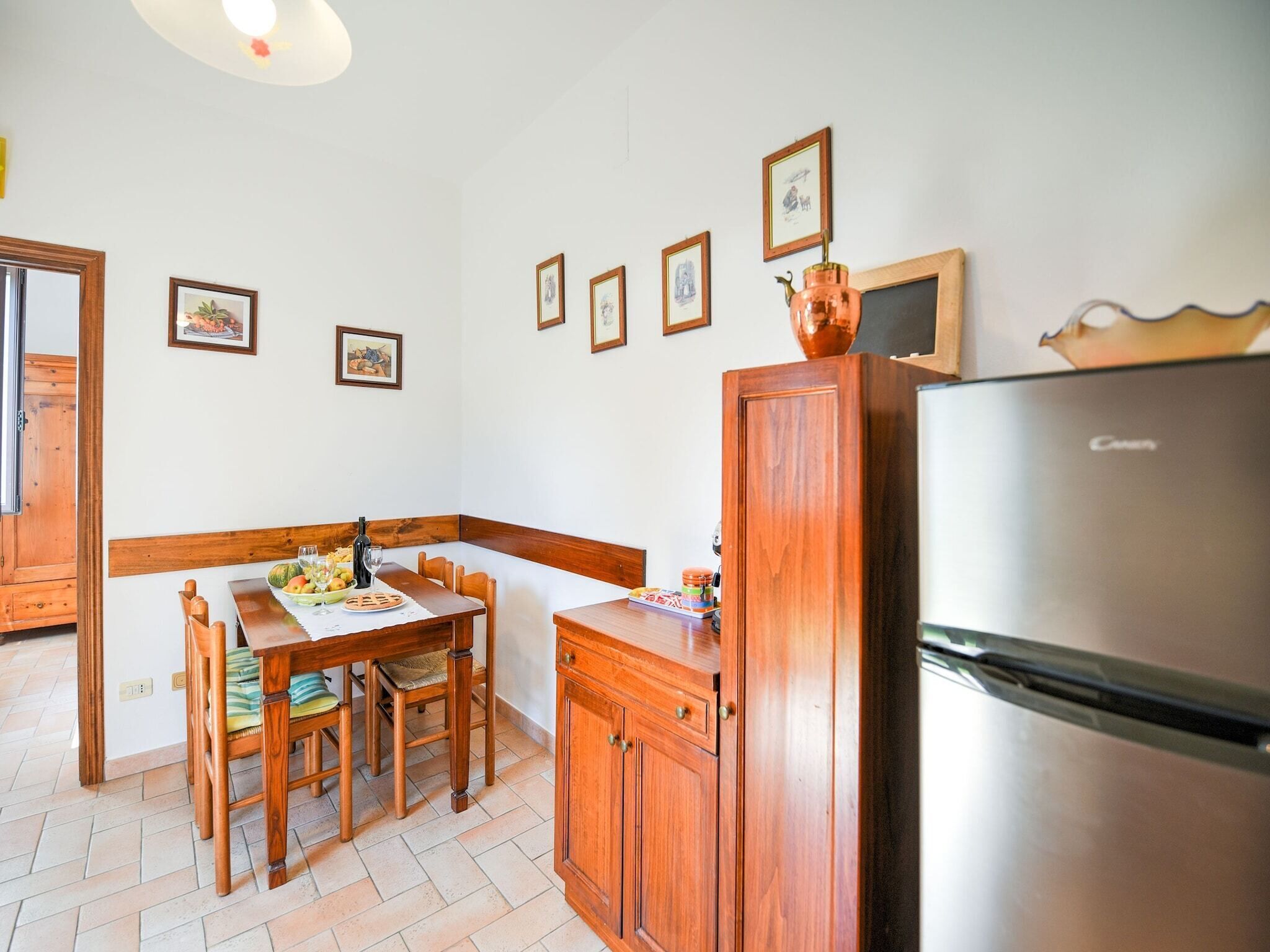 Une cuisine avec des meubles de rangement en bois, un réfrigérateur et une table à manger avec des chaises.