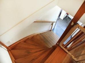 A wooden staircase with a handrail leading to a landing.