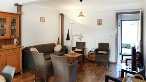Ein geräumiges Wohnzimmer mit Holzboden, einer Couch, zwei Sesseln, einem Couchtisch und einem Schrank.