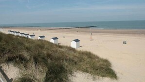 Ein sandiger Strand mit weißen Strandkörben und einem klaren Himmel.