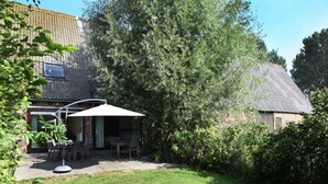 Ein Garten mit einer Terrasse, einem Tisch und Stühlen.