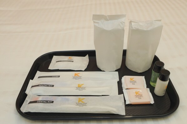 A tray with dental kits, shower caps, and toiletries. - Kansone Hotel And Banquets (Chennai)