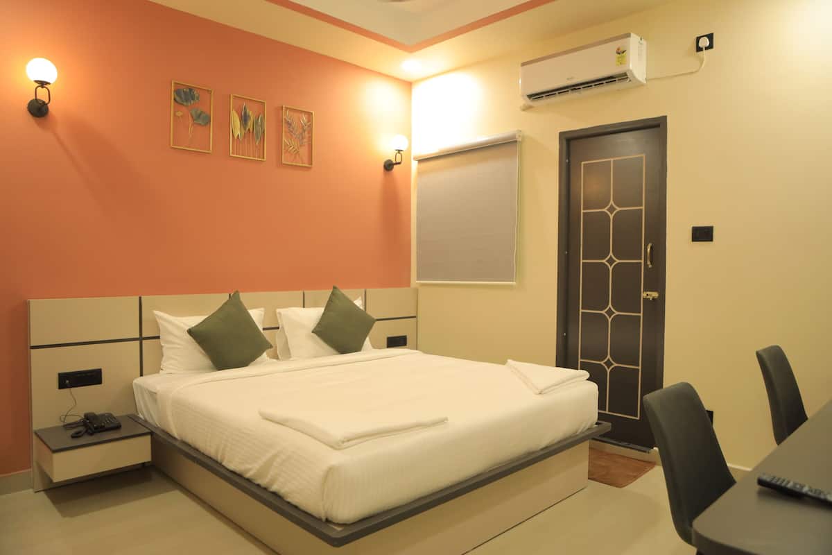 Habitación de hotel con una cama grande, mesitas de noche, un escritorio con una silla y una puerta.