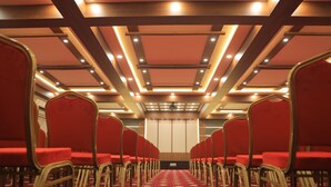Un salón de conferencias con hileras de sillas rojas y una alfombra estampada.