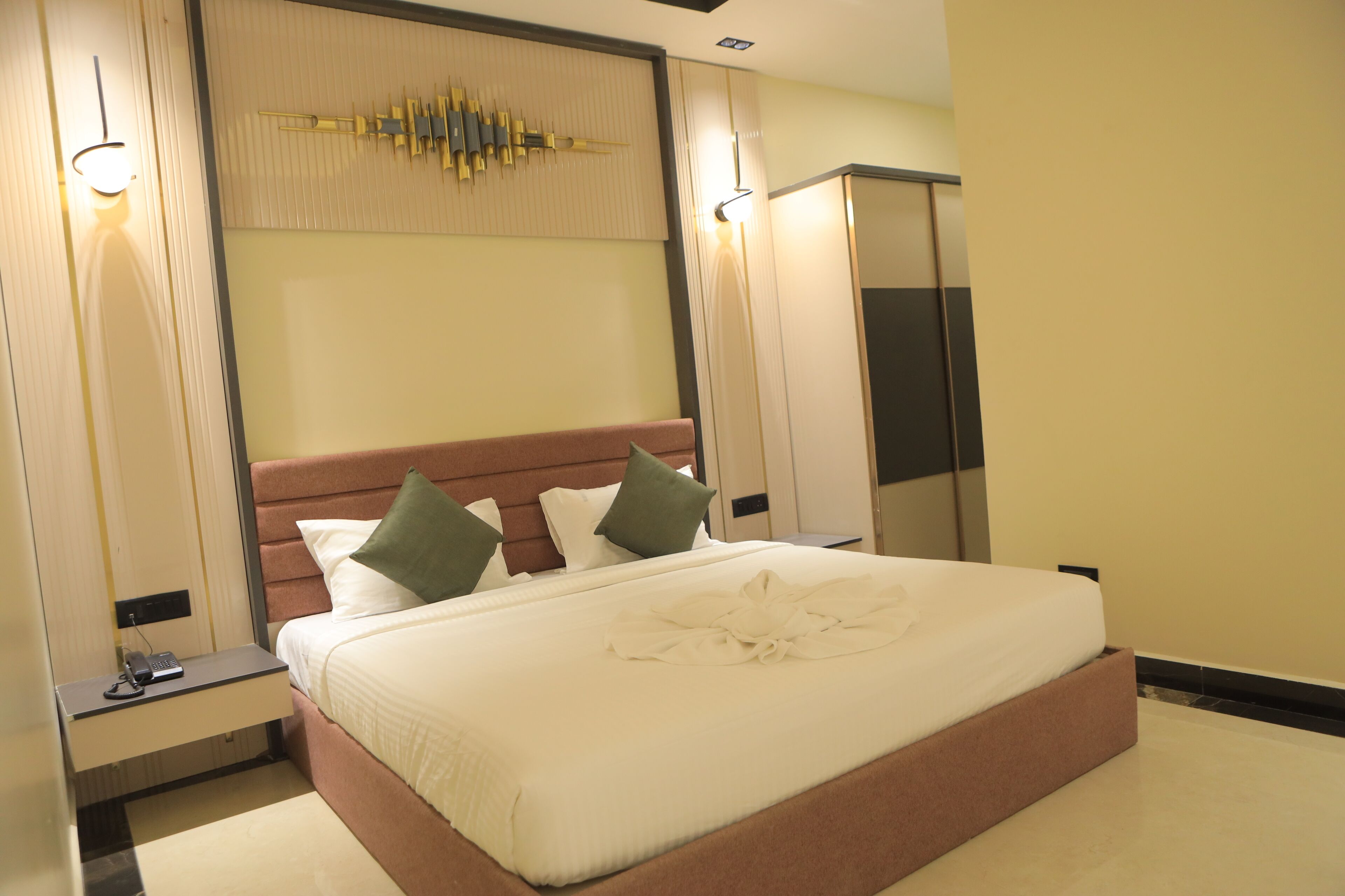 A hotel room with a large bed, a bedside table with a phone, and a mirror.