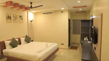 A modern hotel room with a large bed, bedside tables, a flat-screen TV, and a ceiling fan.