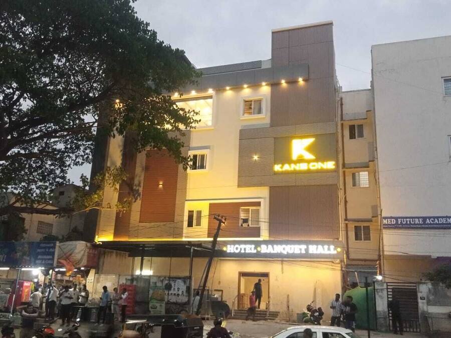 Un hotel con un llamativo letrero con la letra 'K', un acceso cubierto y un área de balcón visible.