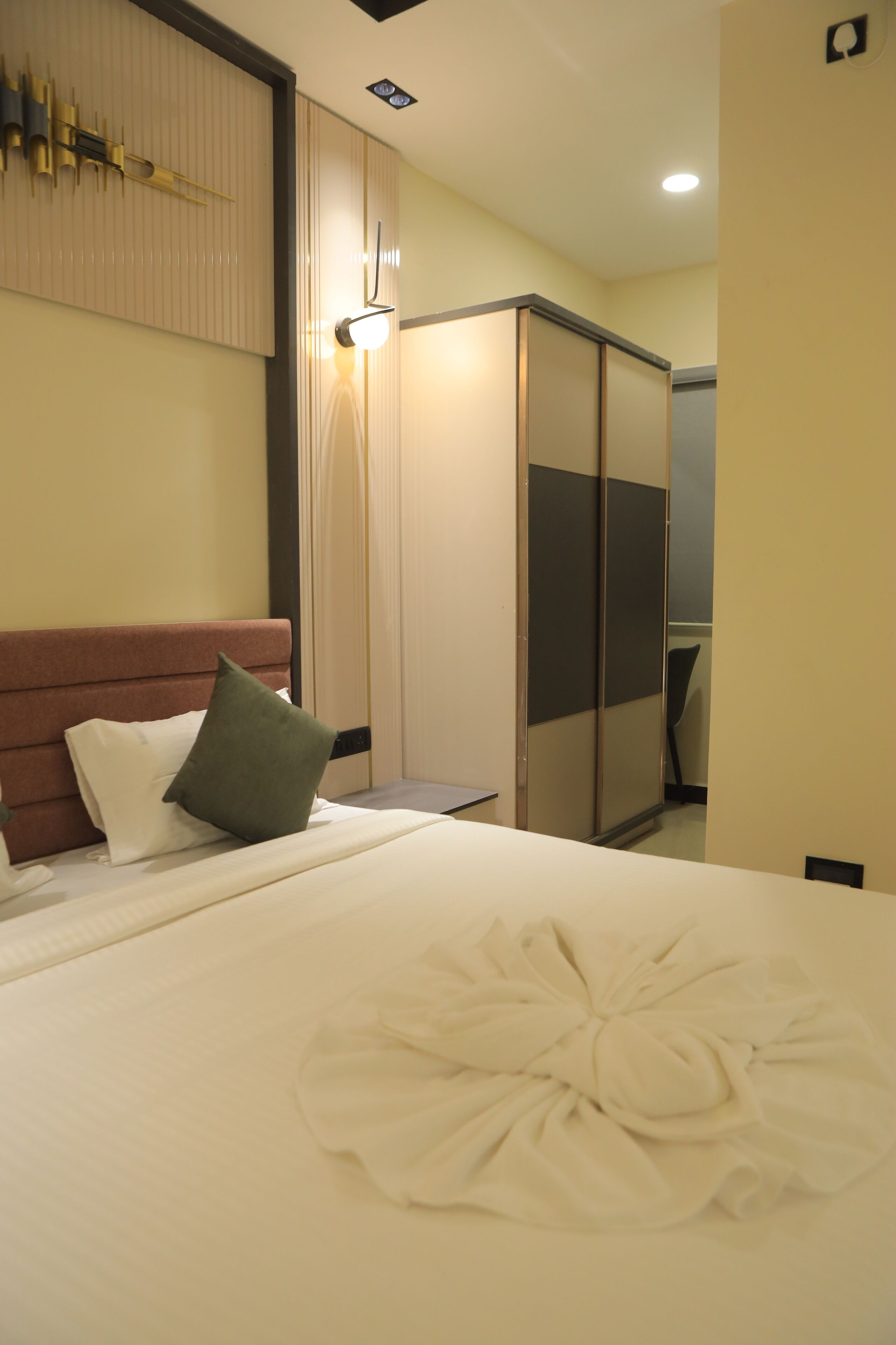 A hotel room with a bed, a wardrobe, and a mirror.