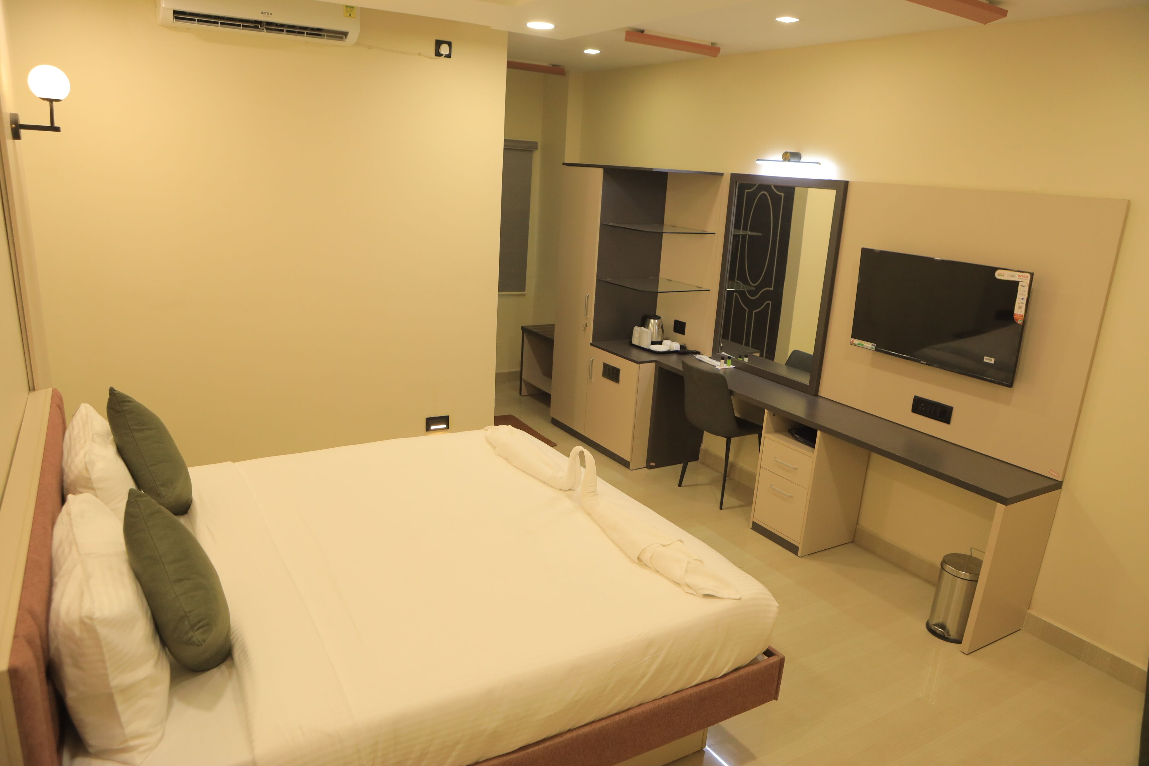 A hotel room with a bed, a desk, a mirror, and a TV.