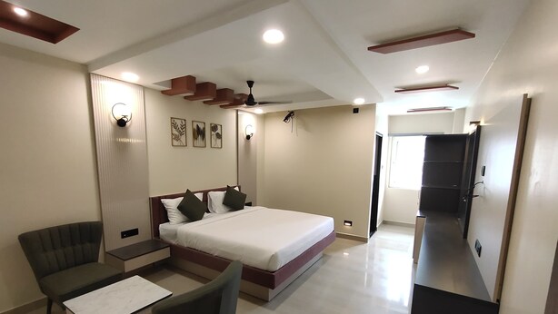 Una habitación de hotel moderna con una cama grande, un escritorio, una silla y un armario.