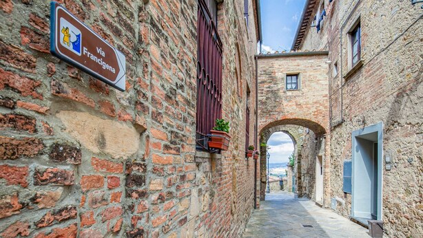 A narrow alleyway with a sign indicating a route via Francigena. - Montaione Harmony: Lodging (Varna - Gambassi Terme-Fi)
