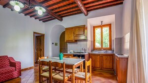 A cozy kitchen with wooden cabinets, a dining table with chairs, and a red sofa. - Montaione Harmony: Lodging (Varna - Gambassi Terme-Fi)