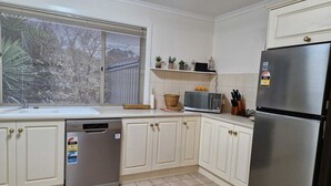 A kitchen with white cabinets, a stainless steel refrigerator, a dishwasher, and a window with blinds. - Adelaide Escape: Two-Storey Home Near City & Hills (Teringie)