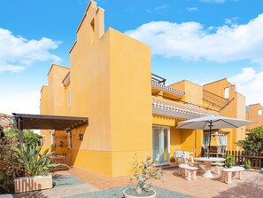 A yellow building with a patio area featuring outdoor furniture and a pergola.