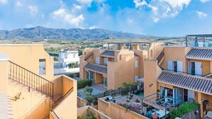 Zona residencial con casas escalonadas, cielo despejado y montañas al fondo.