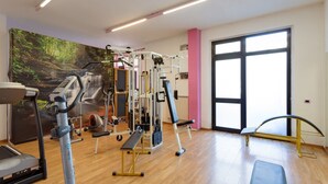 Un gimnasio con máquinas de cardio, equipo de levantamiento de pesas y un ventanal grande.