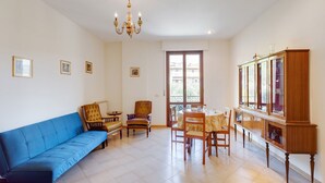 Una sala de estar con un sofá azul, sillas de madera, una mesa de comedor y un aparador.