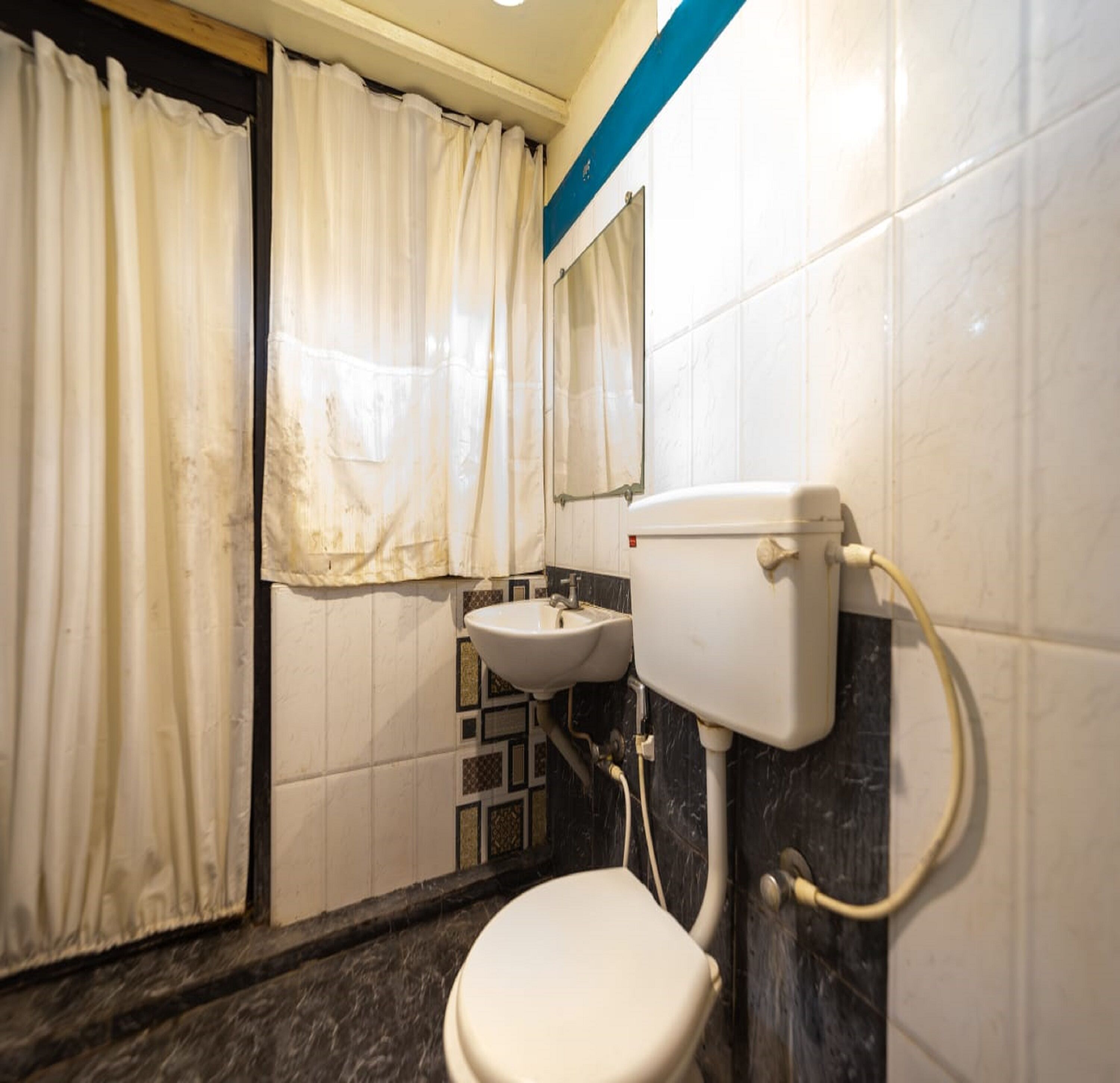 A bathroom with a toilet, sink, and a shower area with curtains.