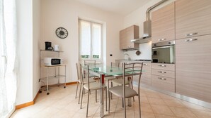 Une cuisine moderne avec une table à manger en verre, des appareils électroménagers en acier inoxydable et des meubles de rangement en bois clair.