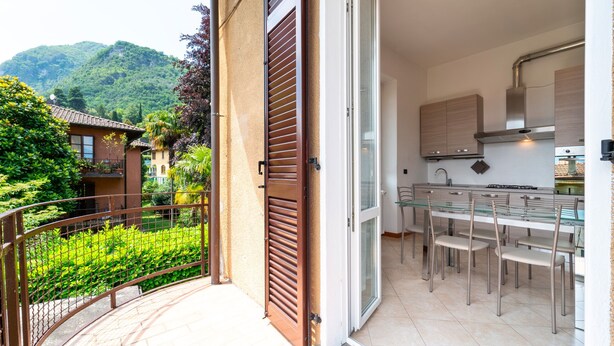 Une cuisine moderne avec une table et des chaises en verre, donnant sur une végétation luxuriante et avec une montagne en arrière-plan.