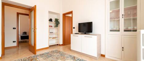 A modern living room with a flat-screen TV, a sofa, a patterned rug, and a cabinet with glass doors.