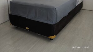Un dormitorio con cama, cabecera, decoración en la pared y ventana.