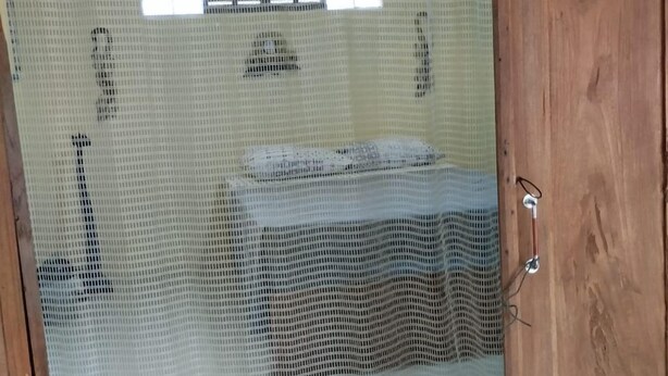 Una habitación con una cama, una puerta de madera y un mosquitero.
