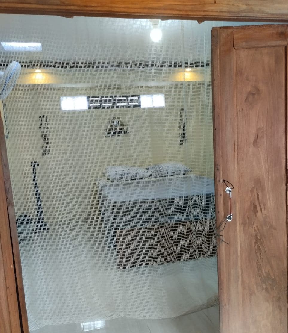 A room with a bed, a wooden door, and a mesh screen.