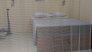 Una habitación con cama, ventana y estante en la pared.