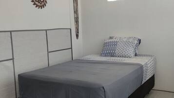 A bedroom with a bed, a headboard, a wall decoration, and a window.