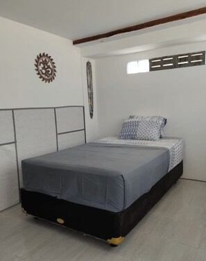 A bedroom with a bed, a headboard, a wall decoration, and a window. - Adem Huis Samen (Sumbermulyo)