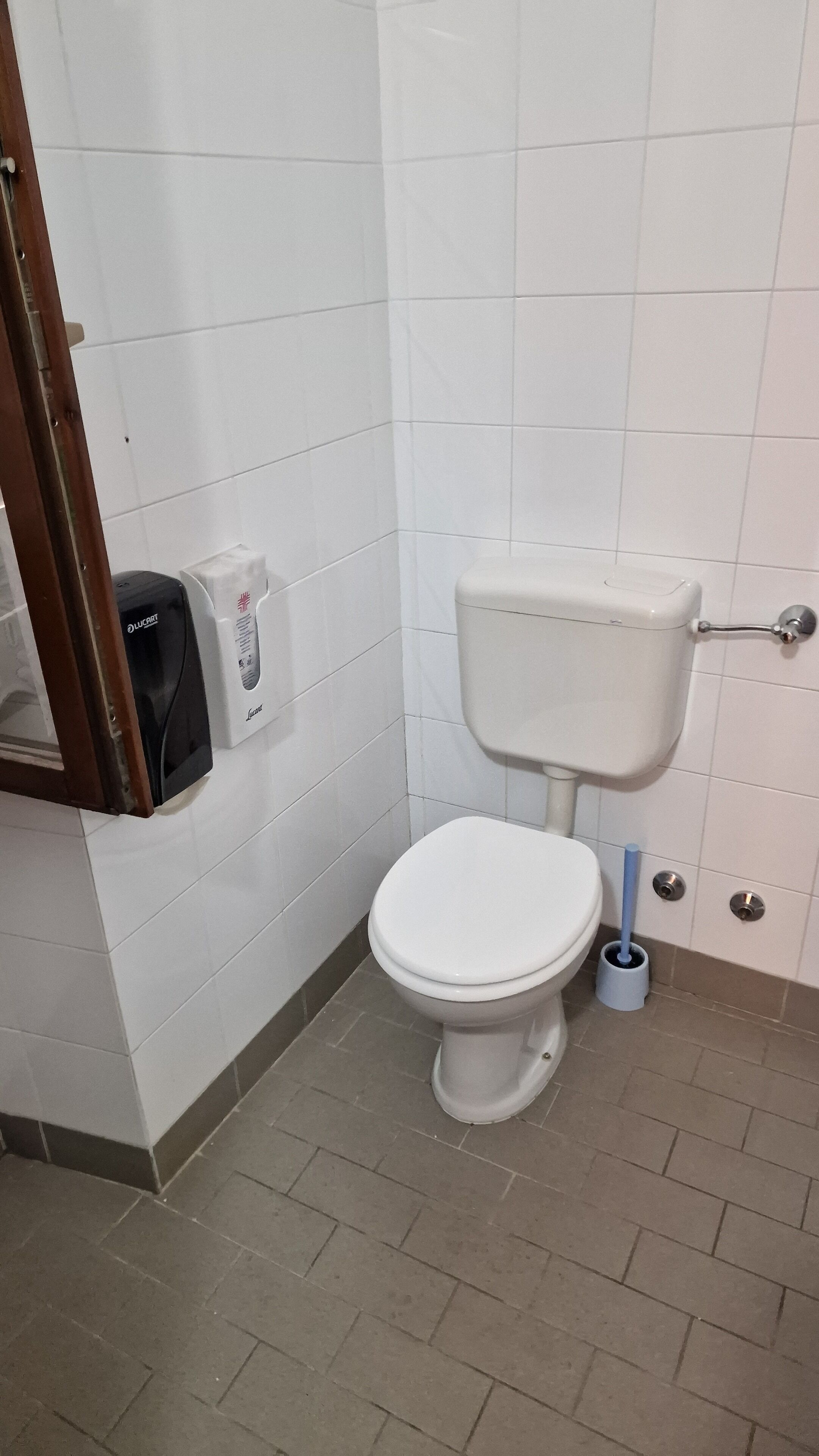 Un bagno con un water bianco, un asciugatore d'aria e un dispenser di carta.