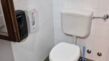 Un bagno con un water bianco, un asciugatore d'aria e un dispenser di carta.