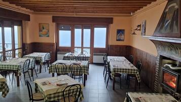 Ein Restaurant mit mehreren Essplätzen, einem Kamin und großen Fenstern mit Ausblick.