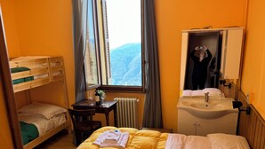 A room with a bunk bed, a desk with a bottle of wine and glasses, a sink, and a mirror.