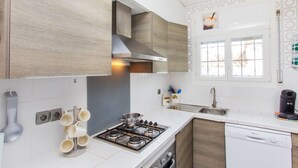 A modern kitchen with a gas stove, a dishwasher, and a window with decorative elements. - La Bahia by Interhome (L'Escala)