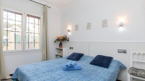 A bedroom with a bed, a nightstand, a window with curtains, and wall-mounted lights. - La Bahia by Interhome (L'Escala)