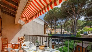 Un balcone con un tavolo apparecchiato per due, affacciato su una zona residenziale con alberi e auto parcheggiate.