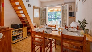 Zona pranzo con mobili in legno, televisore e vista esterna.