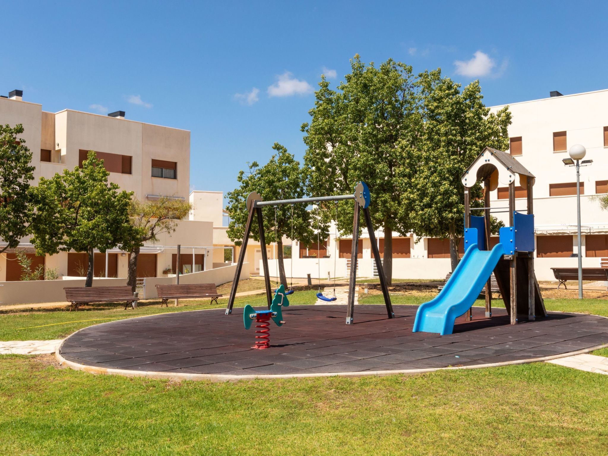 Ein Spielplatz mit Schaukeln, einer Rutsche und einer Bank.