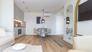Ein modernes Wohnzimmer mit Essbereich, einer Couch, einem Couchtisch und einem an der Wand befestigten Fernseher.