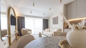 Ein modernes Wohnzimmer mit einem runden Tisch, einer Couch und einem an der Wand befestigten Fernseher.