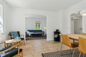 A modern living room with a sofa, chairs, a dining table, and a fireplace. - Old local house from 1904 with natural garden. (Tranekær)